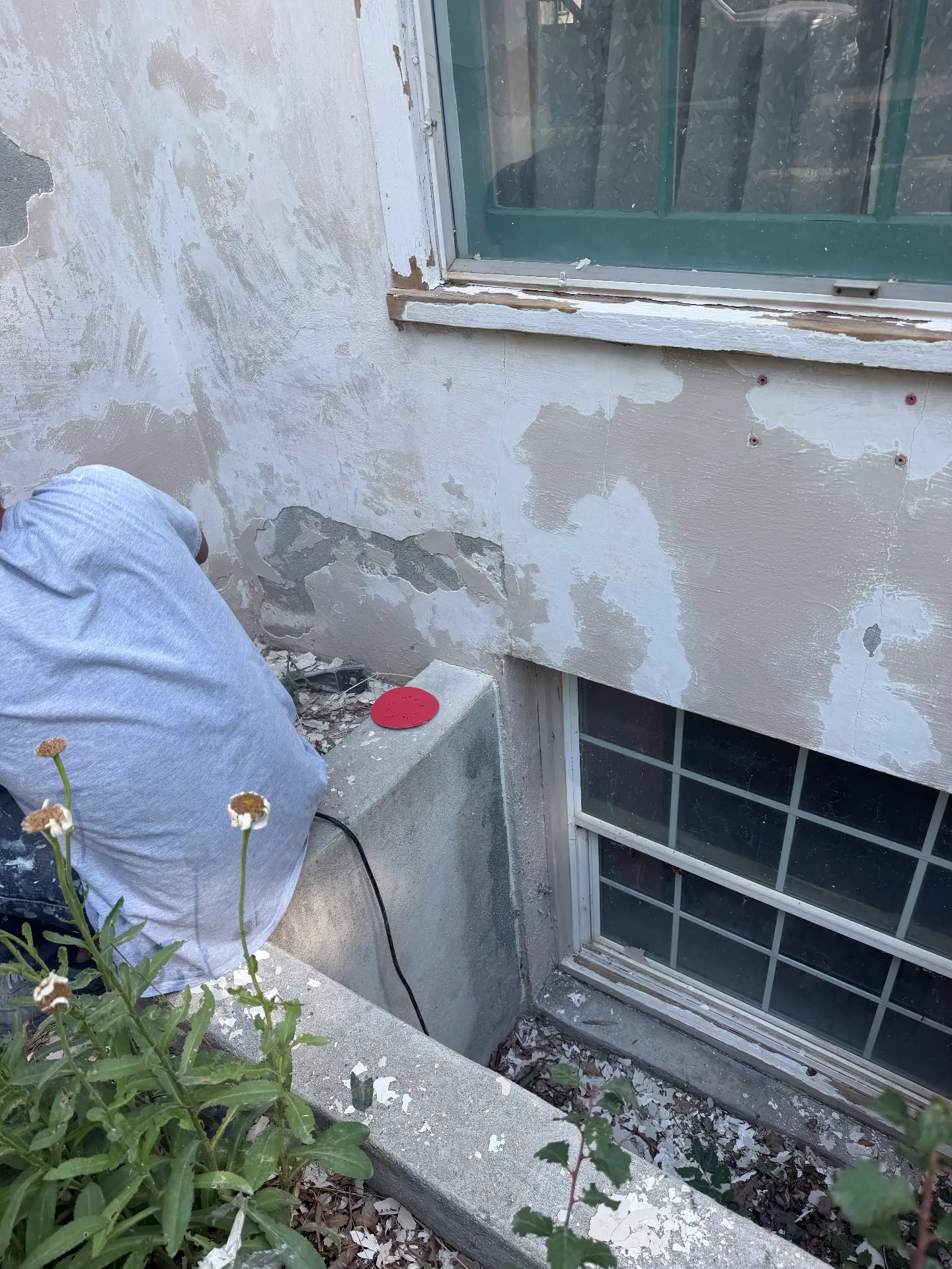 Failed exterior coating being removed around a window